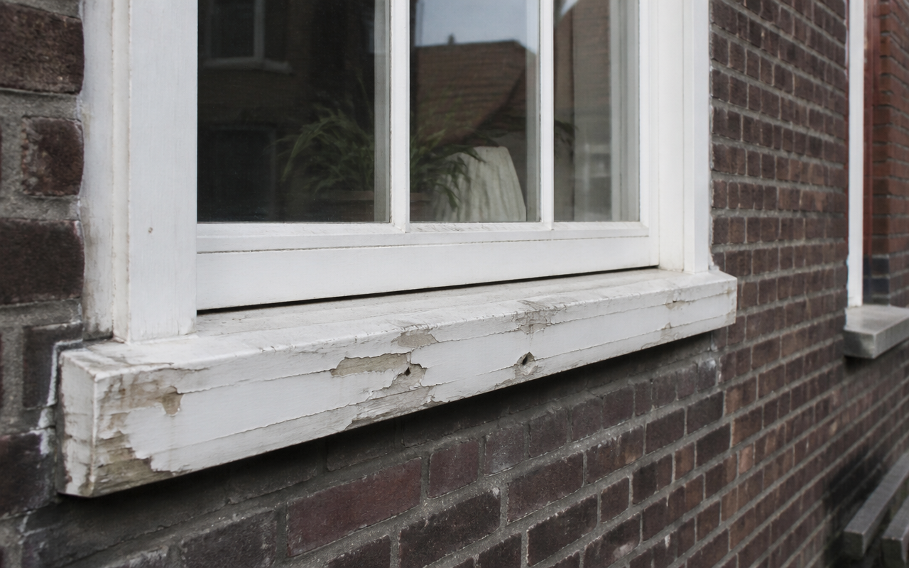 Houtrot reparatie Nijmegen - verweerde onderdorpel van een wit houten kozijn in een Nijmeegse bakstenen gevel, hersteld door L.T.J. Schilderwerken